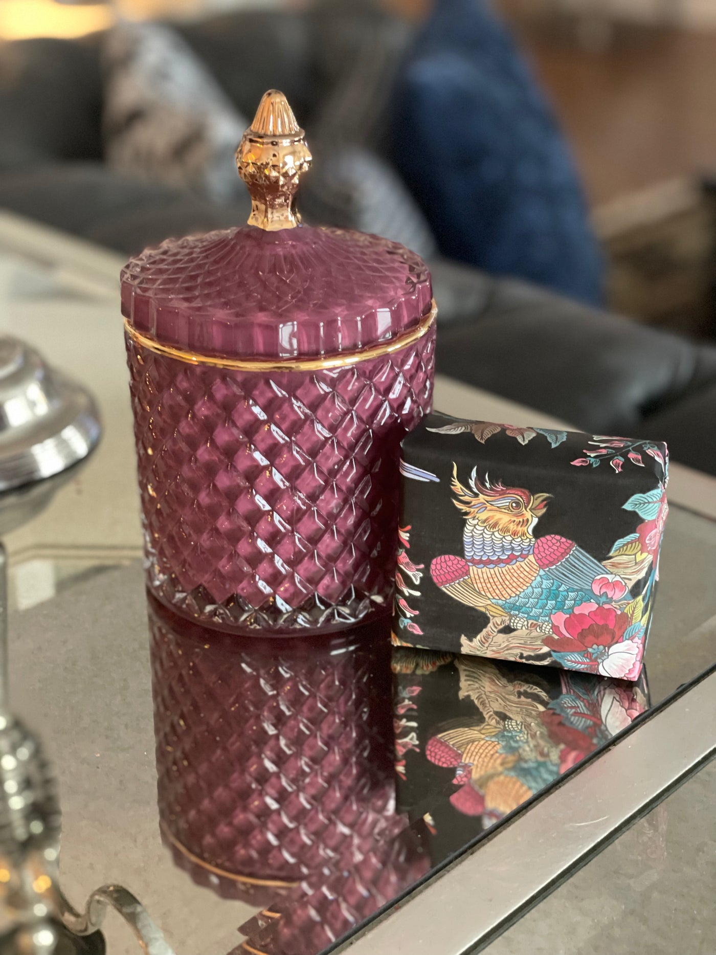 Rose glass lidded vessel with gold trim displayed beside a hand-wrapped soap