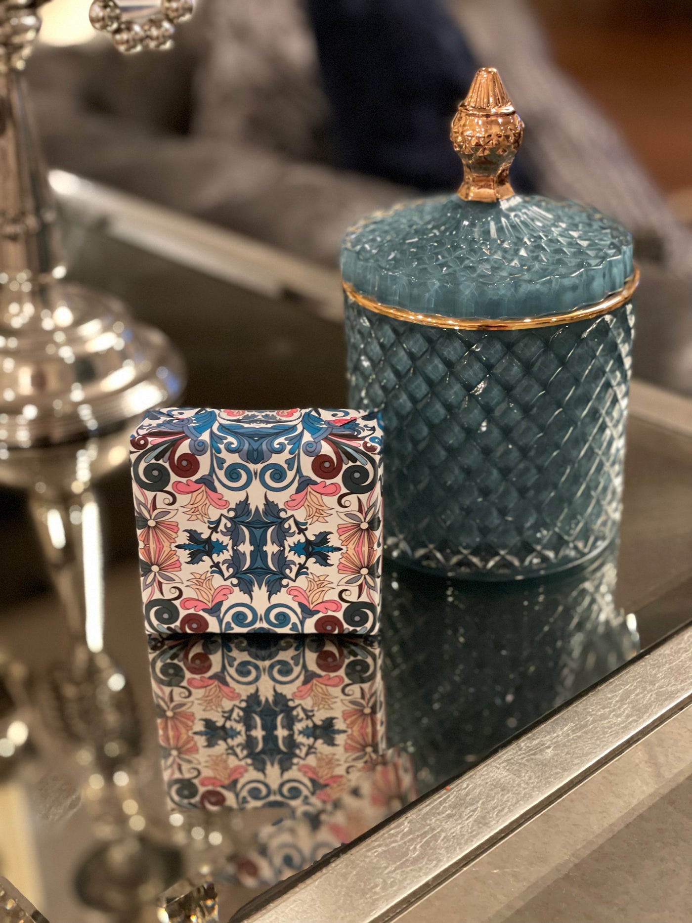 Blue glass lidded vessel with gold trim displayed beside a hand-wrapped soap