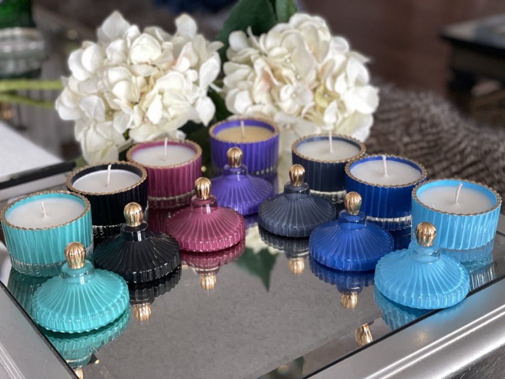 Colorful Seventh Sense Home vessels arranged on a reflective surface with white hydrangeas
